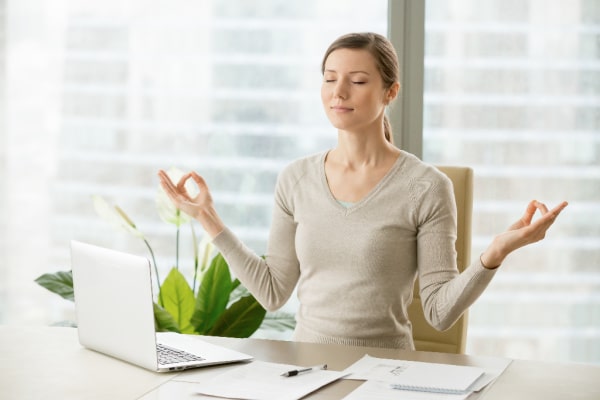 woman doing yoga pose at desk at work