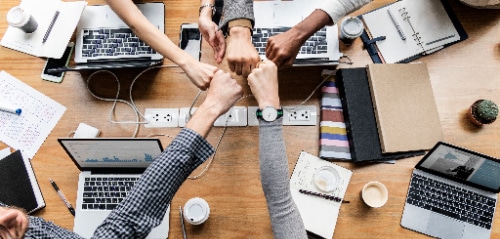 coworkers putting fists in a circle in team building gesture