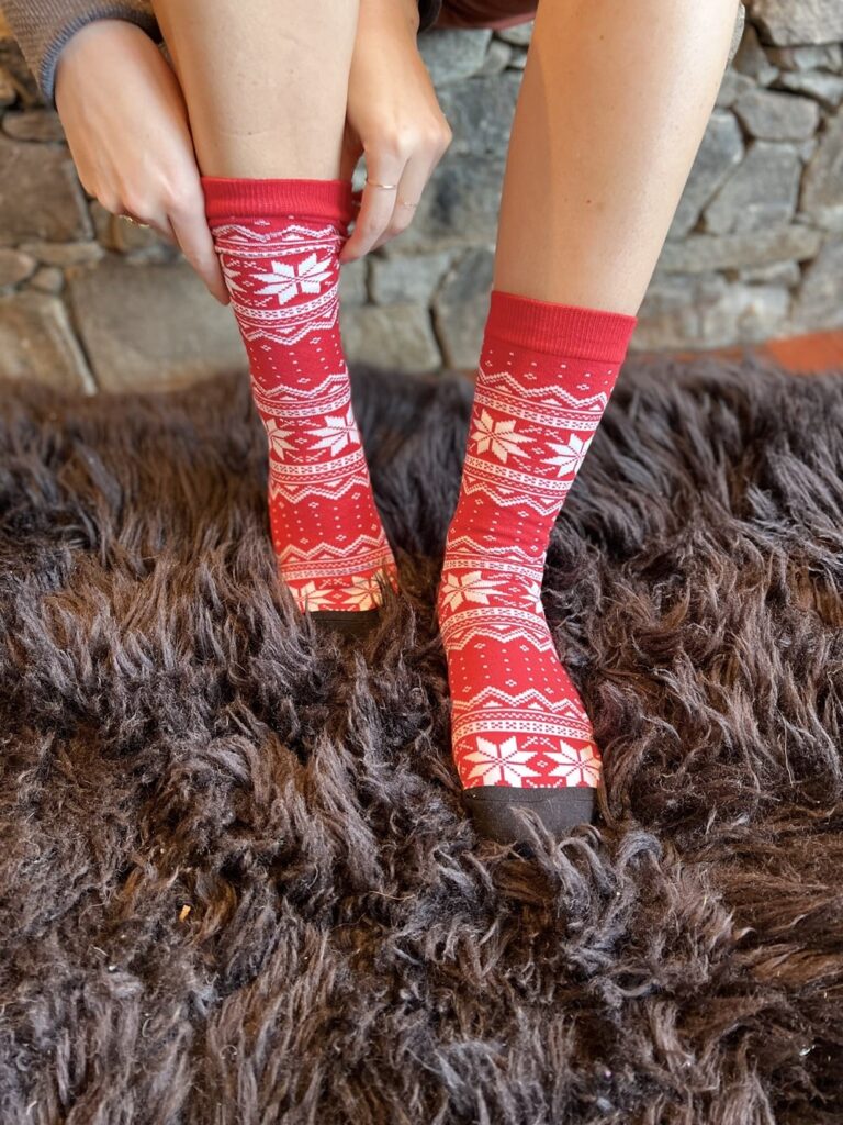 Someone pulling up a pair of Christmas custom socks with white snowflake on red blackground