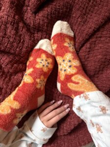 someone wearing a pair of orange fuzzy socks with christmas snowflake and gingerbread design