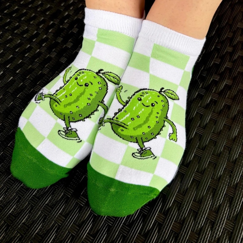 a pair of custom crew socks with a cartoon pickle on a white-and-lime-green grid pattern