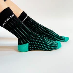 custom branded socks from spirit sox usa, featuring a black background, geometric teal gradient pattern, and teal sole and tips with white brand name around the cuff