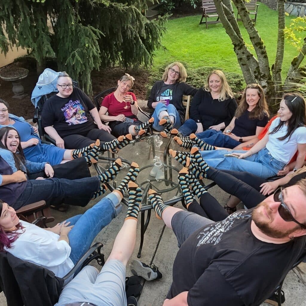 A small business crew showing off their custom branded socks by lifting their feet and form a circle at an outing