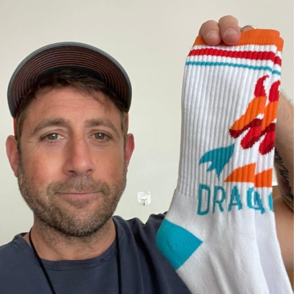 a man holding a pair of custom socks for the dragons