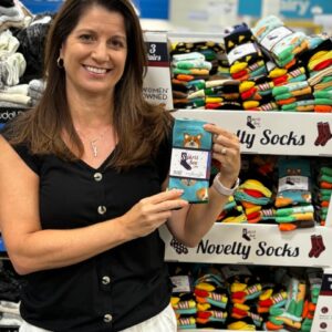 Lisa Riggs holds up a pair of Spirit Sox socks in front of a retail display.