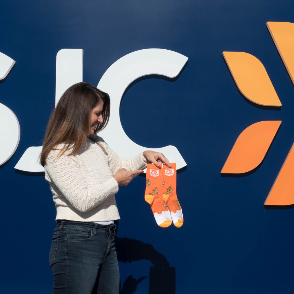 Lisa of spirit sox holding a pair of custom design socks
