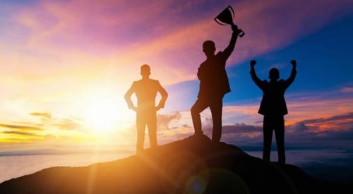 people cheering at the top of a mountain with trophy in hand