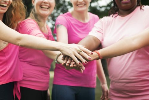 women in pink shirts touching hands