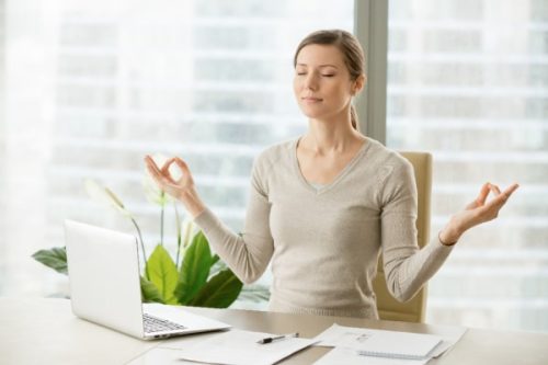 woman doing yoga pose at desk at work