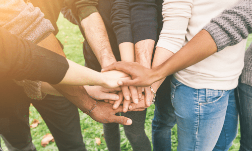 people in a group with hands gathered together in middle of group